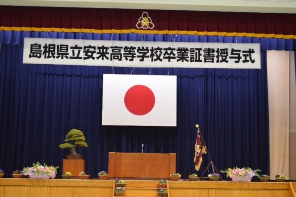 卒業証書授与式当日の国旗とともに飾り付けられた壇上の写真