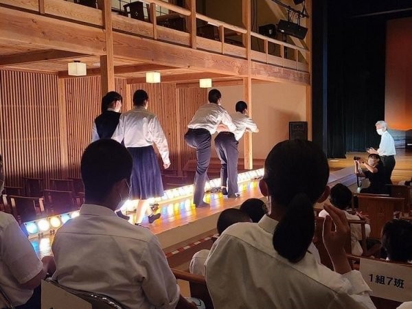 花道から照明をあびながら、どじょうすくい踊りのBGMに合わせて入場する生徒の写真