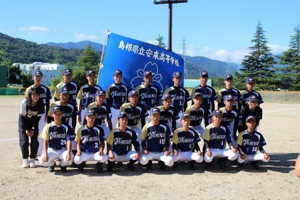 島根県立安来高等学校の校旗をバッグに整列する選手たちの写真